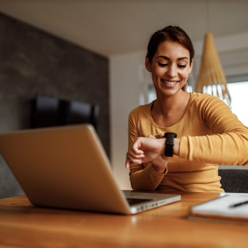 Portrait of business woman, looking at her wrist watch.